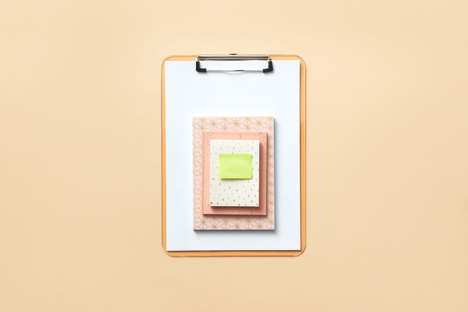 A clipboard holding a stack of blank notepads with a sticky note on top