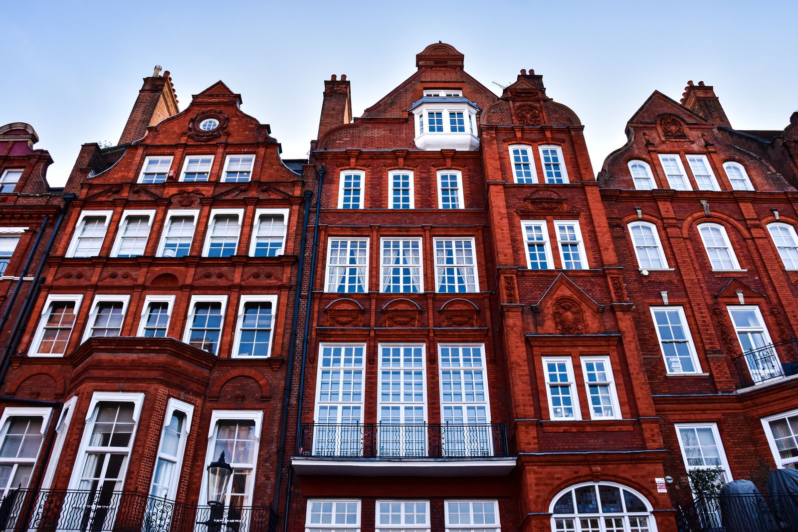 A red-brick mansion block of flats with ornate gables and white sash windows